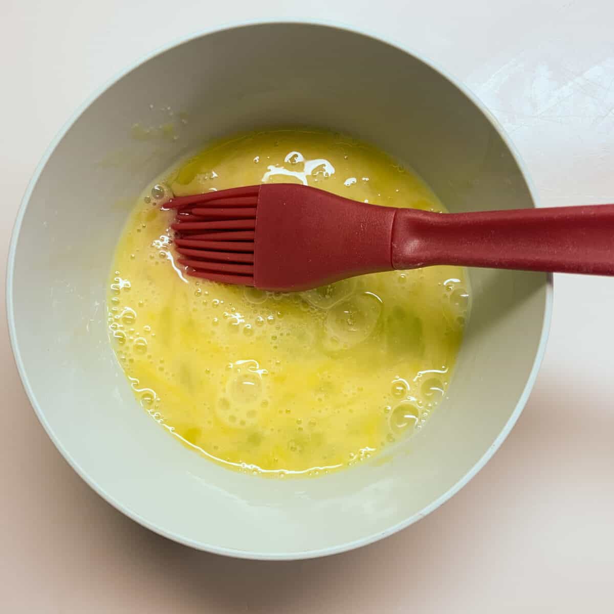 egg wash in small bowl with red brush