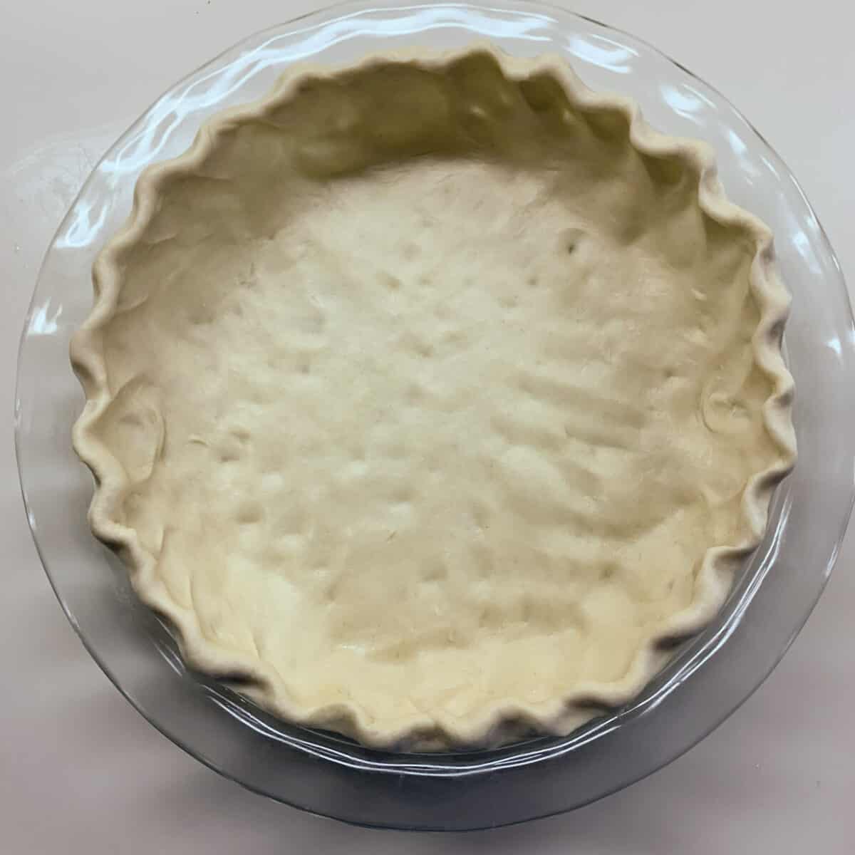 pie dough stretched in glass pan