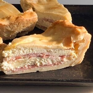 wedge of Italian easter pie (pizza rustica) on black pan