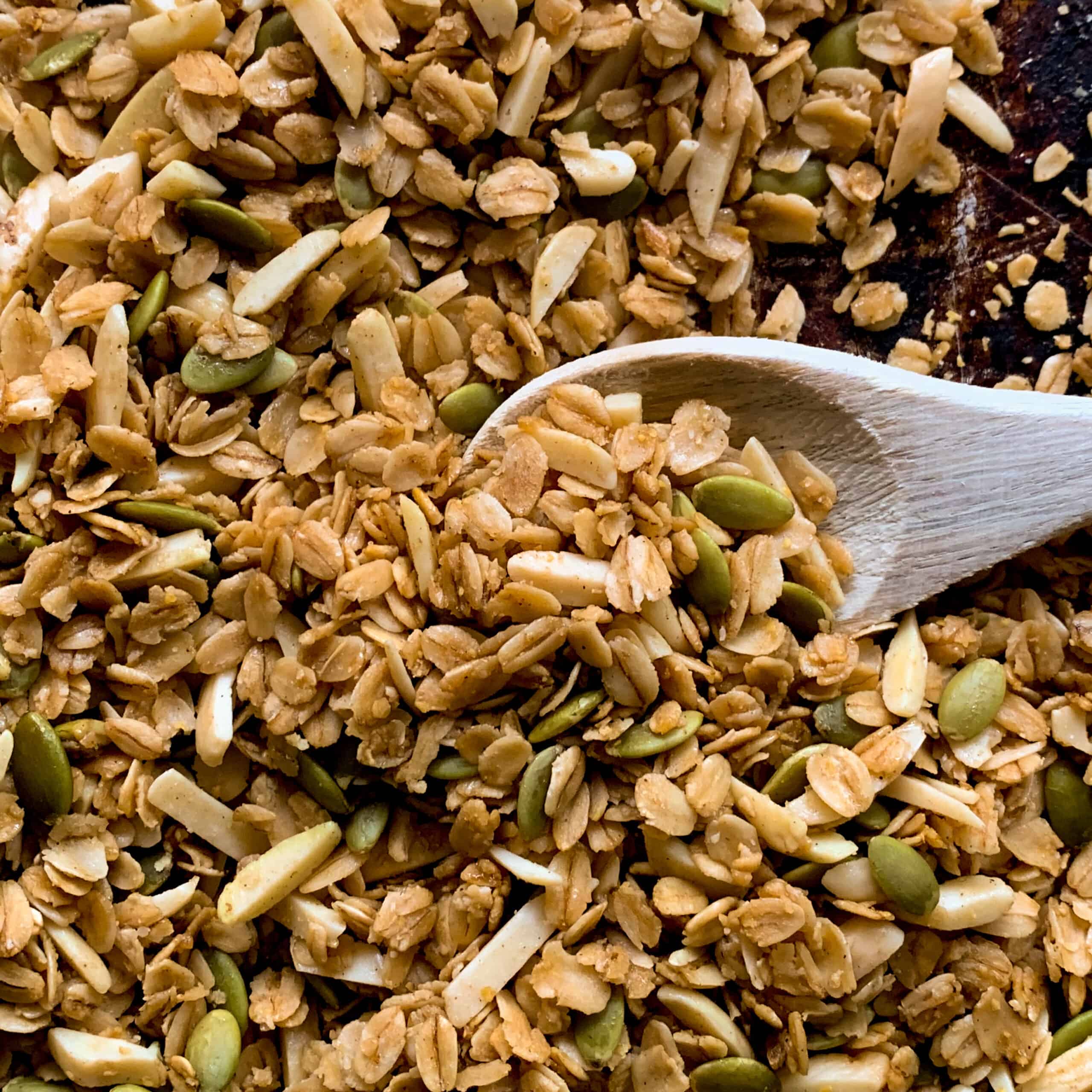 Close up view of homemade granola with nuts and seeds and wooden spoon