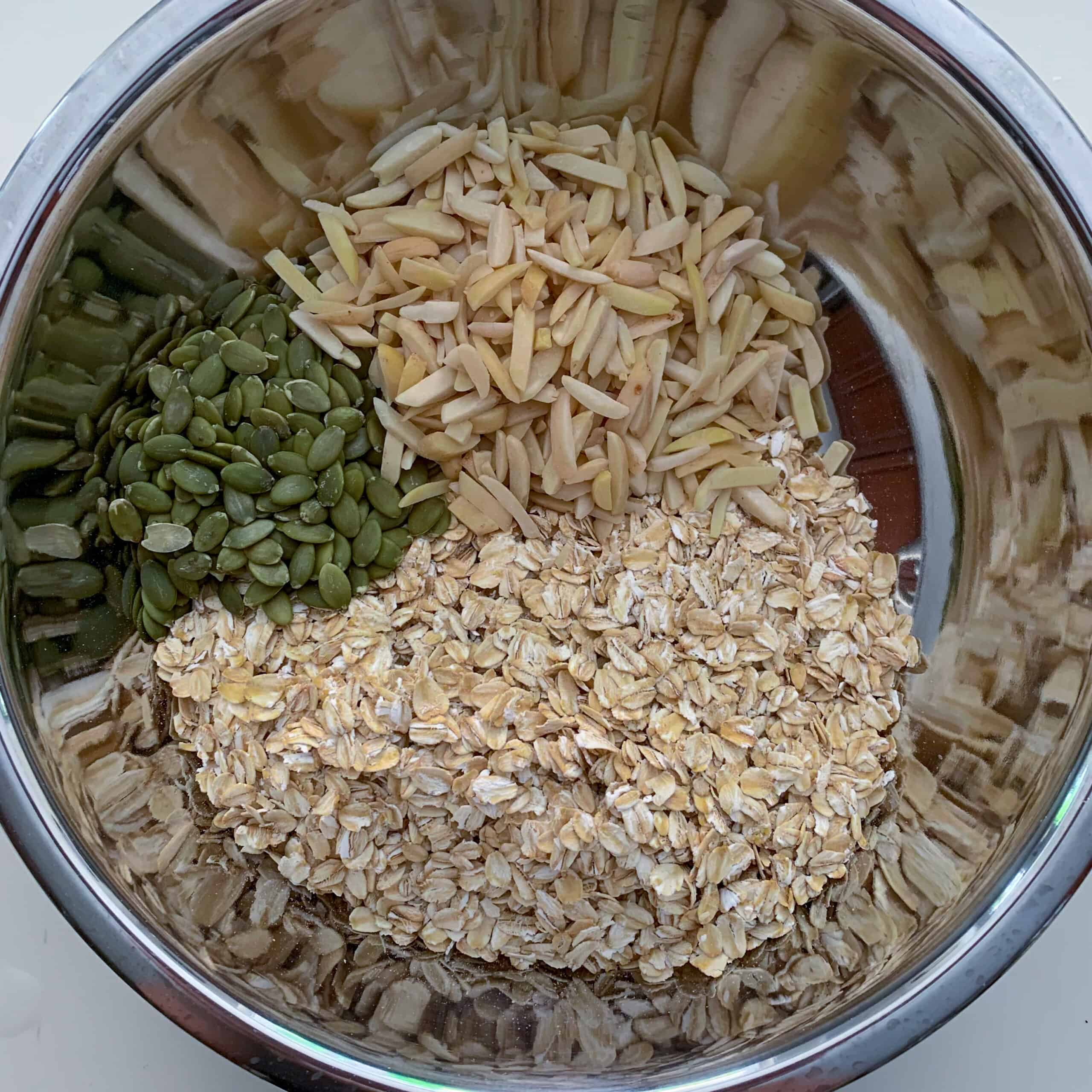 dry ingredients for granola in silver bowl (oats, slivered almonds and pumpkin seeds)