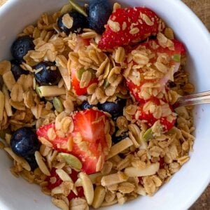 Top view of granola with white bowl with berries