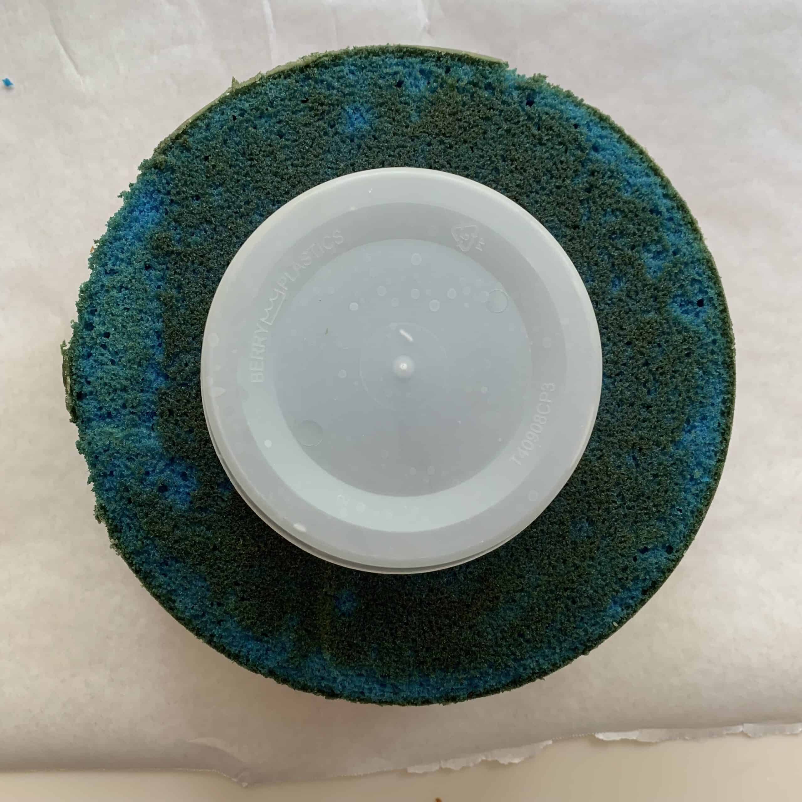 blue cake layer with plastic lid centered on top