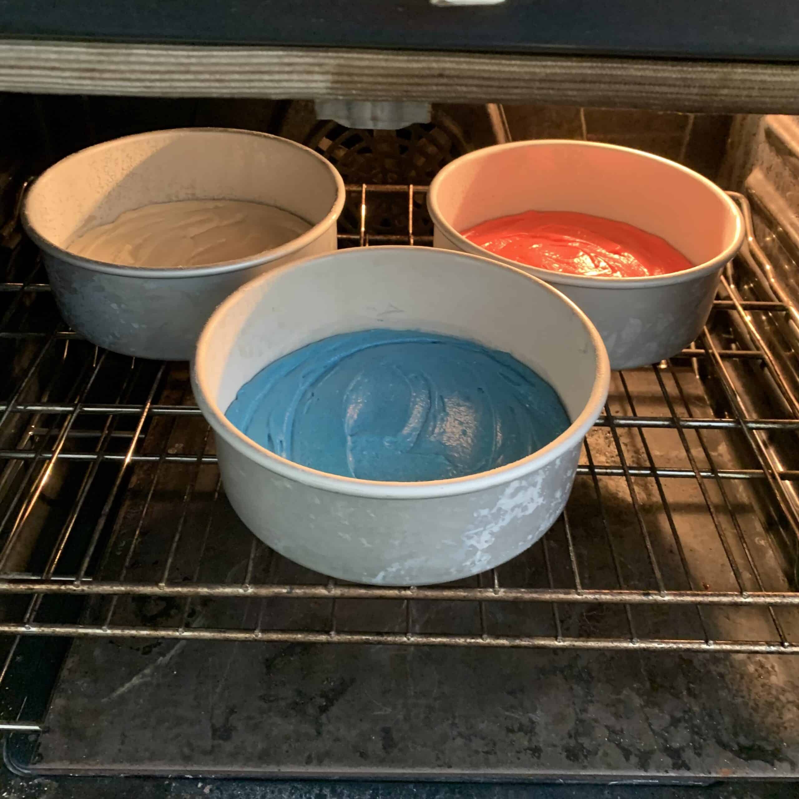 cake pans in oven with red blue and white batters