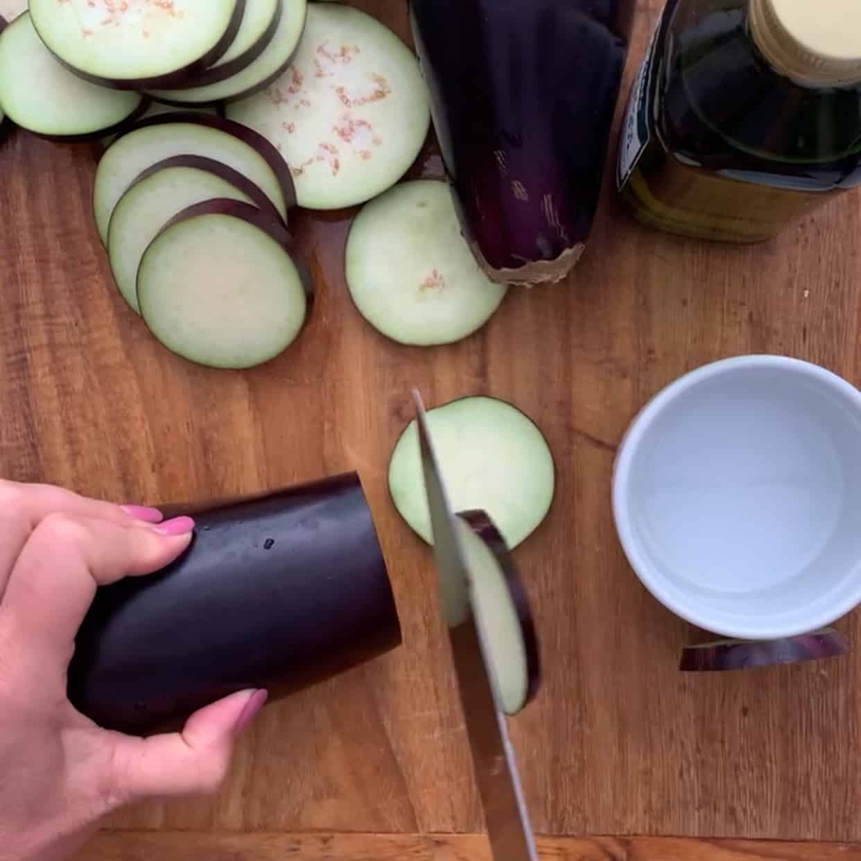slicing eggplant on wooden cutting board