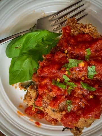 top view of baked eggplant parm with fork on white dish