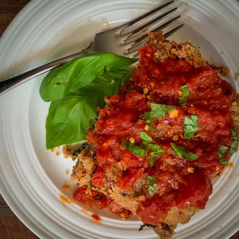 top view of baked eggplant parm with fork on white dish