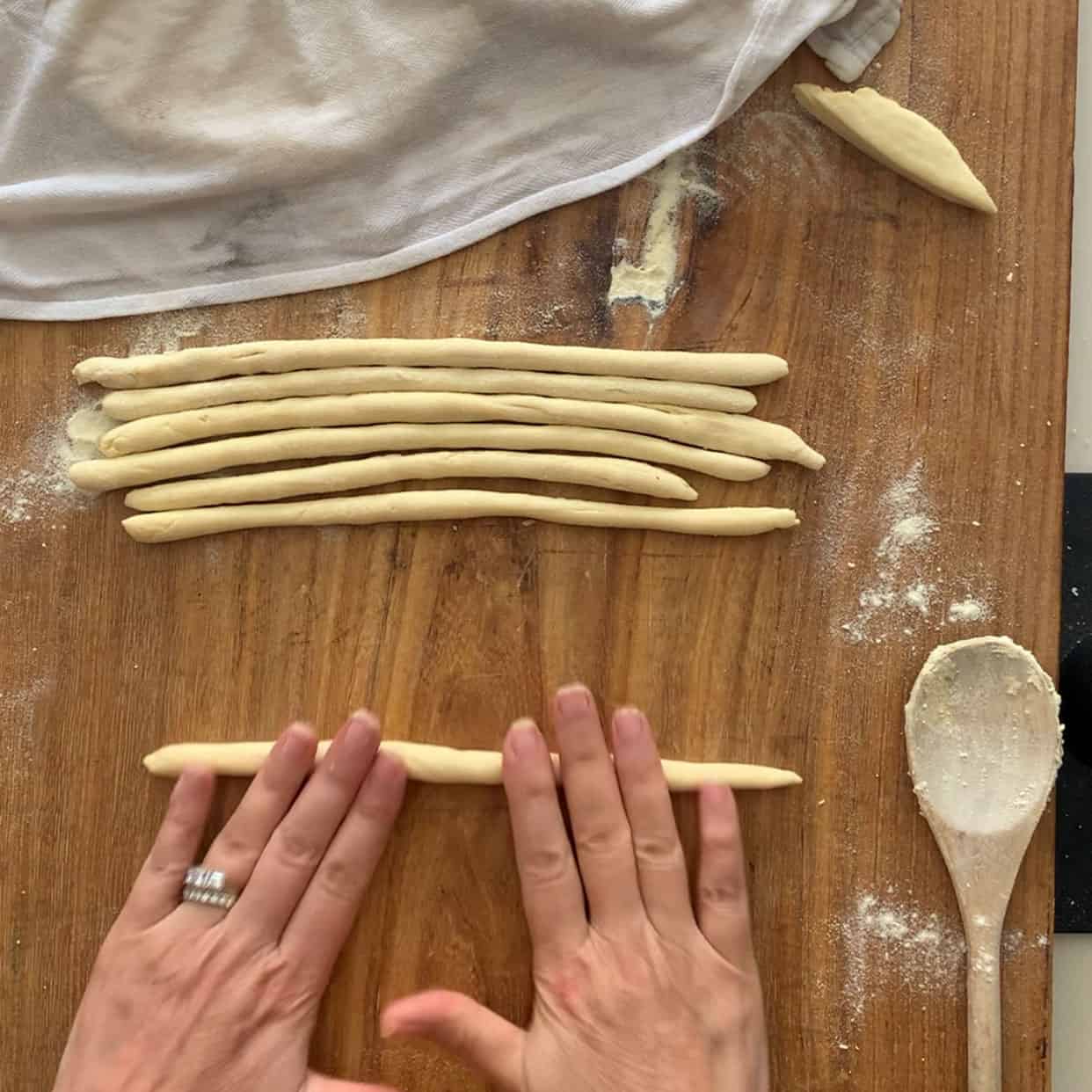 rolling dough into long ropes on wooden board
