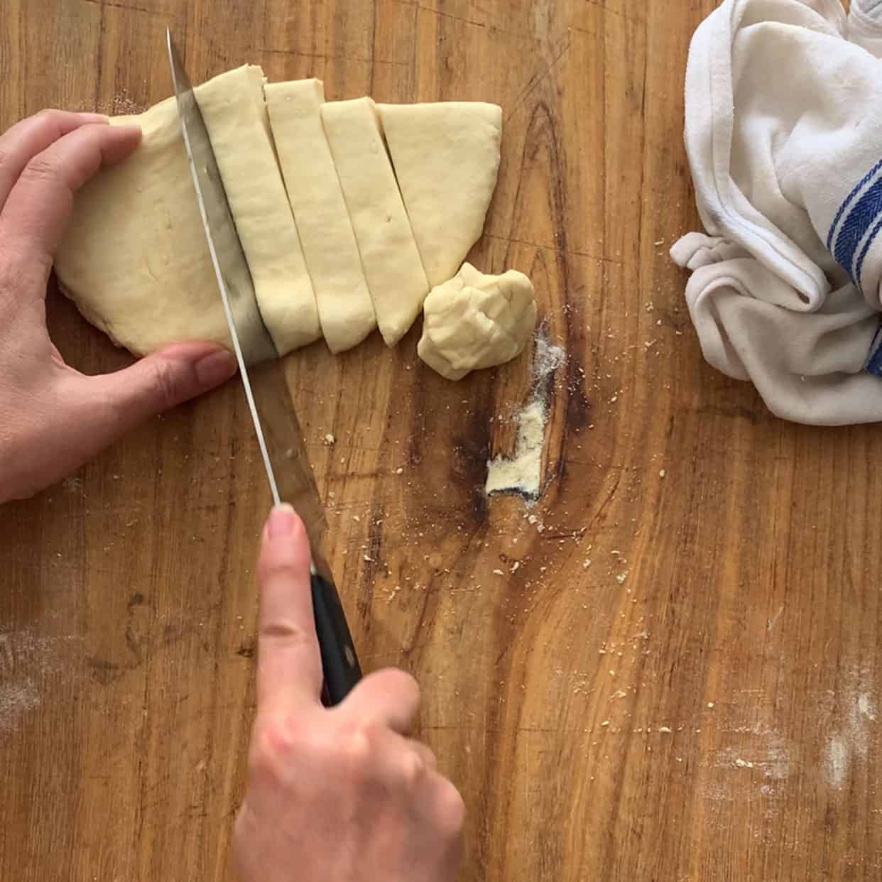 slicing pasta dough on wooden board