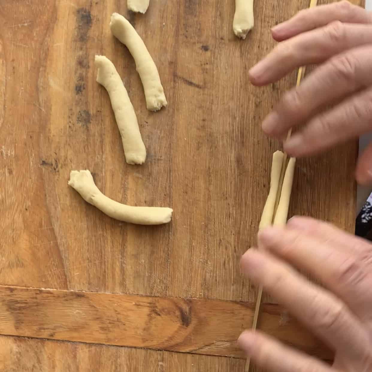 Pressing fusilli iron into center of dough preparing to roll on wooden board