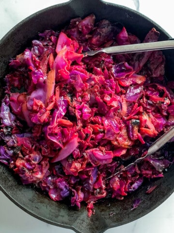 top view of roasted red cabbage in cast iron pan with tongs
