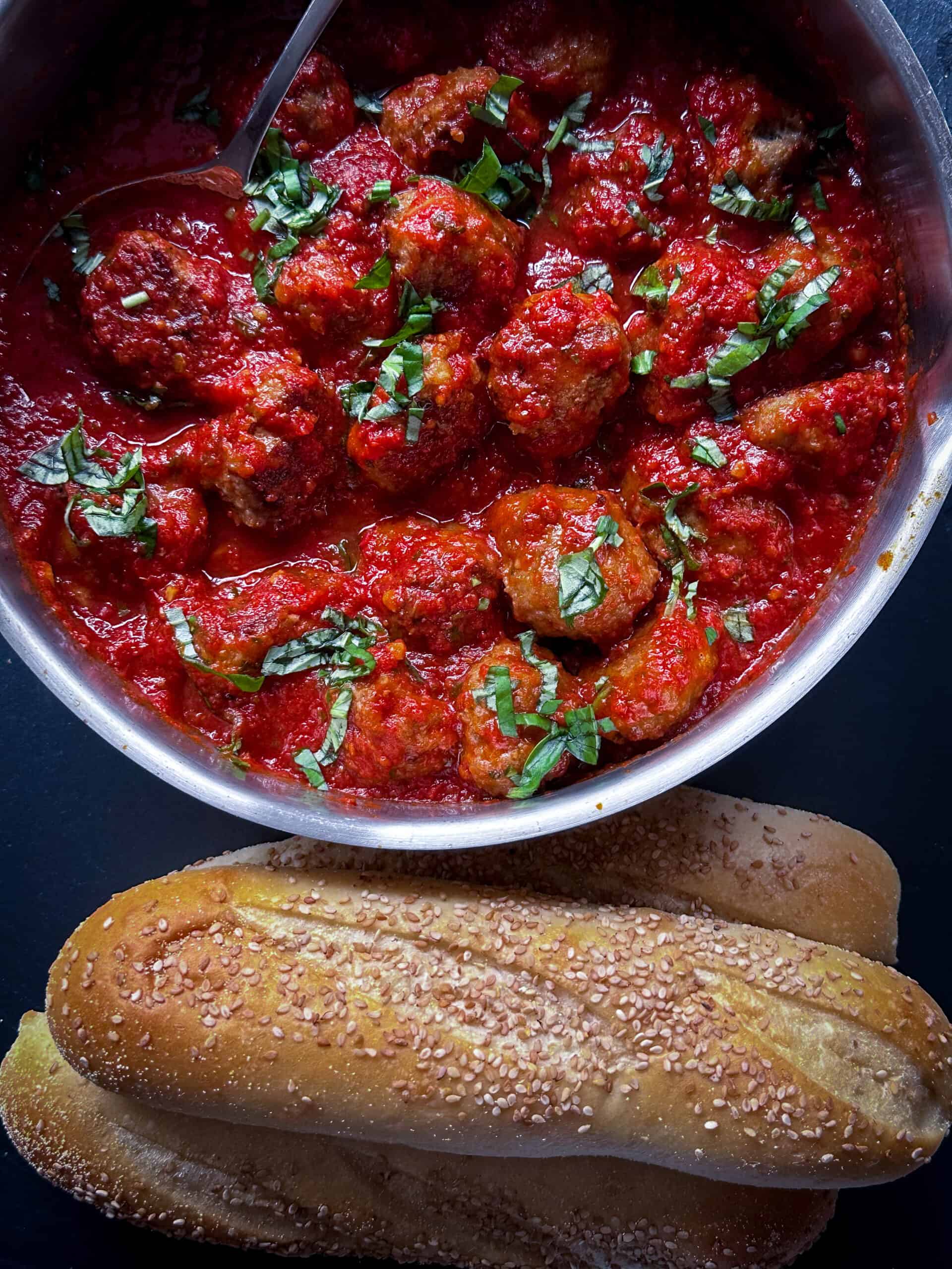 meatballs in pan with seeded rolls nearby