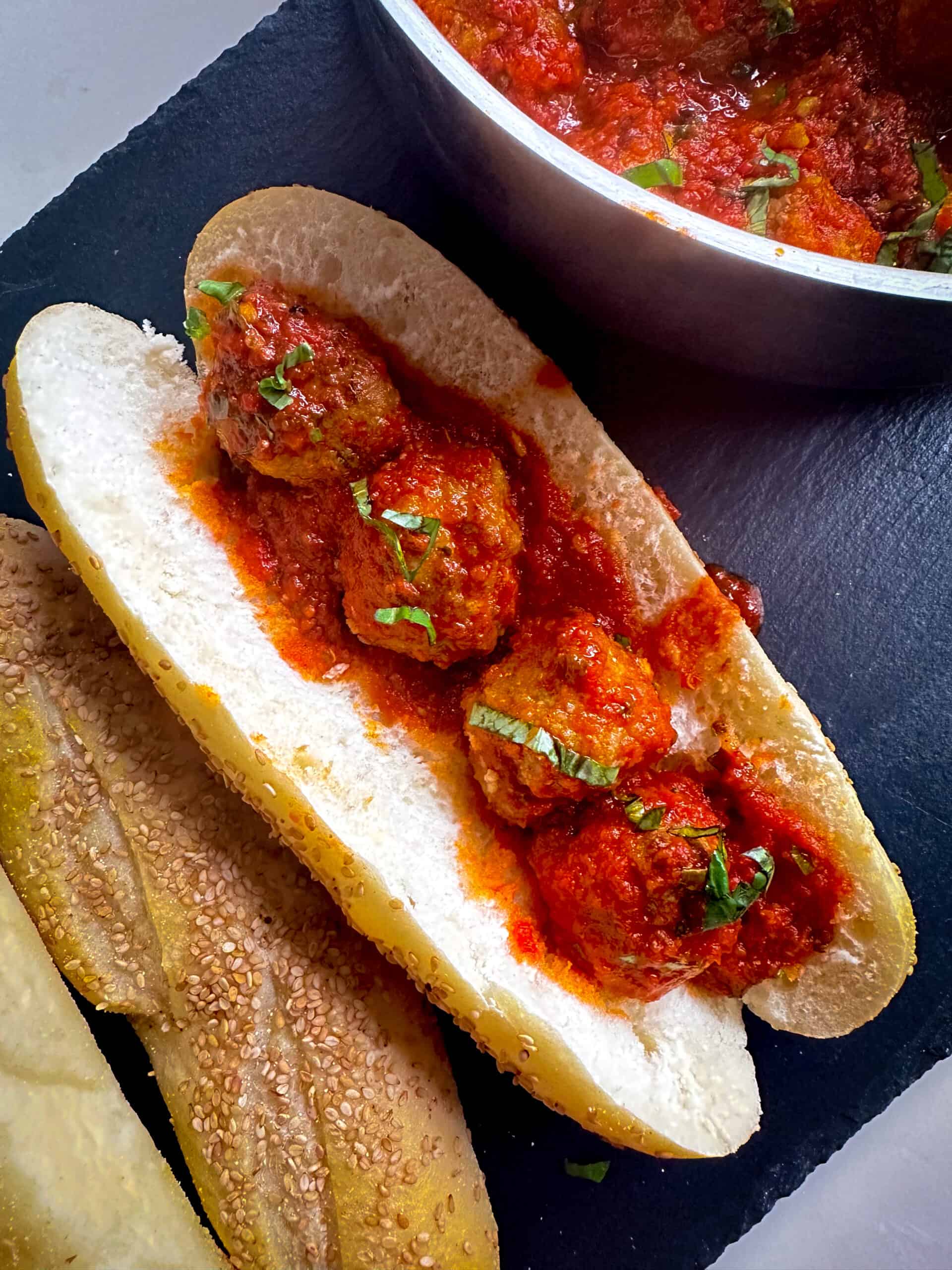 meatballs sandwich on black board with extra rolls