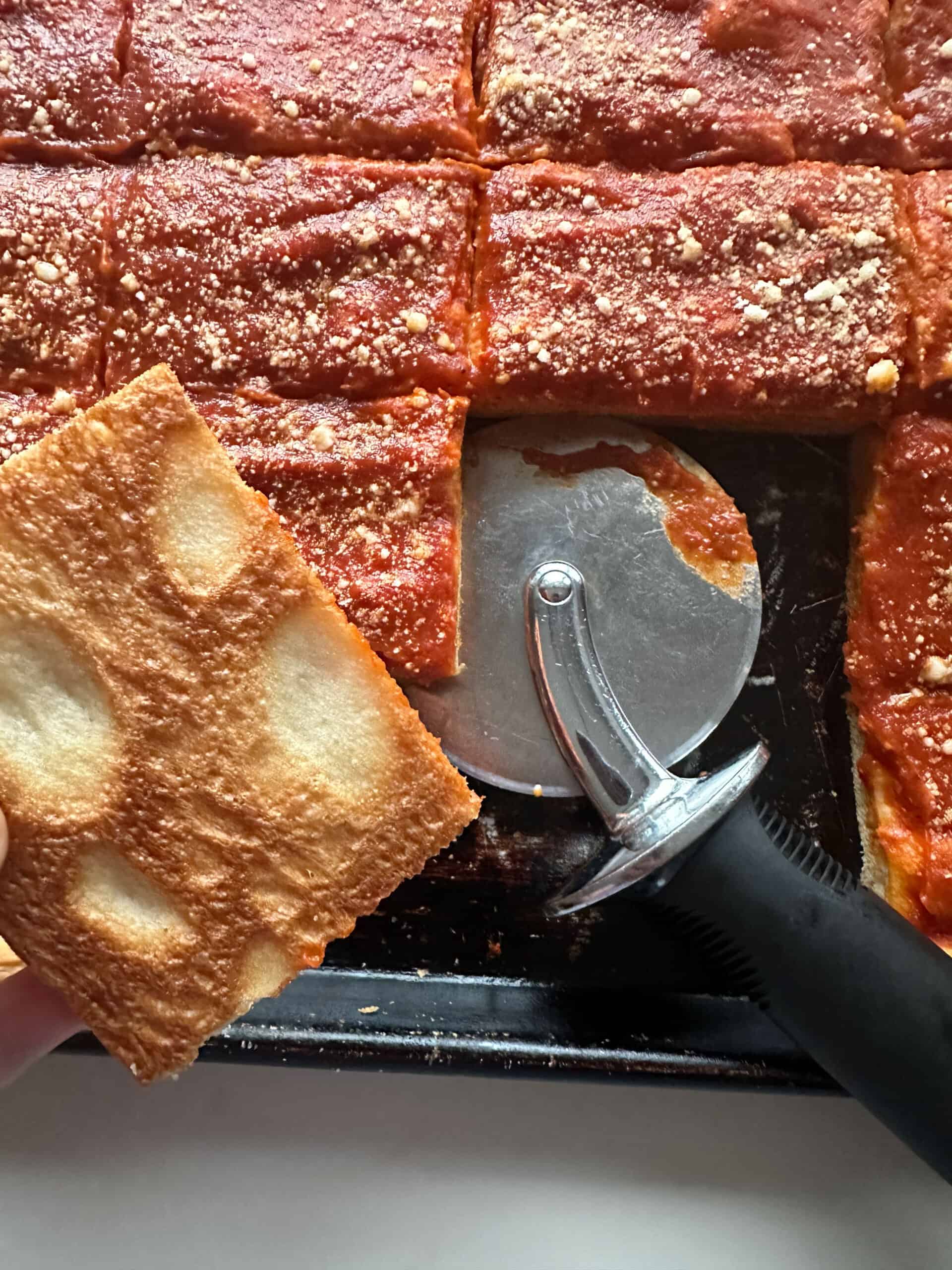 tomato pie with pizza cutter and piece showing under crust