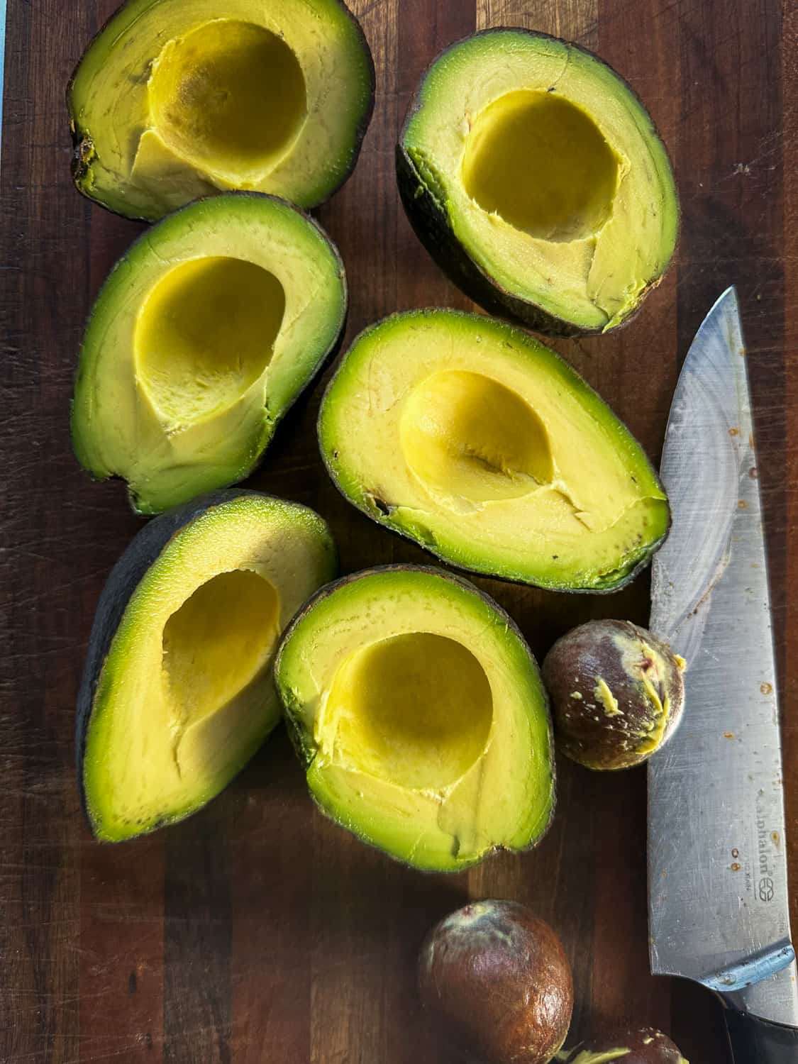 Avocado halves with no pit on black tray