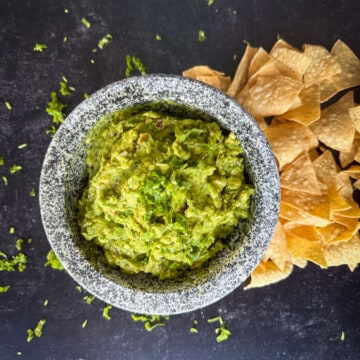 top view of guacamole with chips on black background