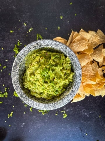 top view of guacamole with chips on black background