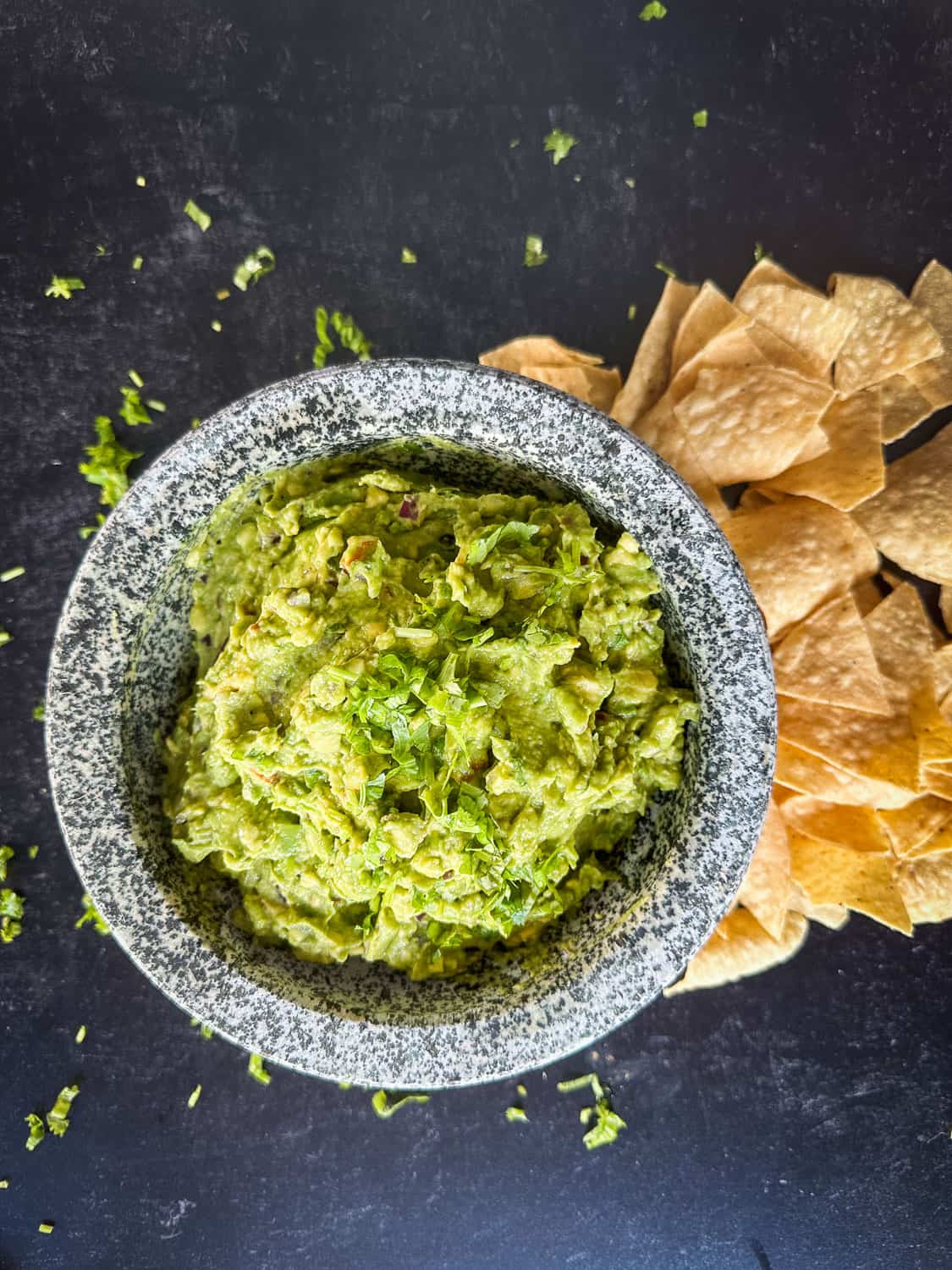 top view of guacamole with chips on black background 