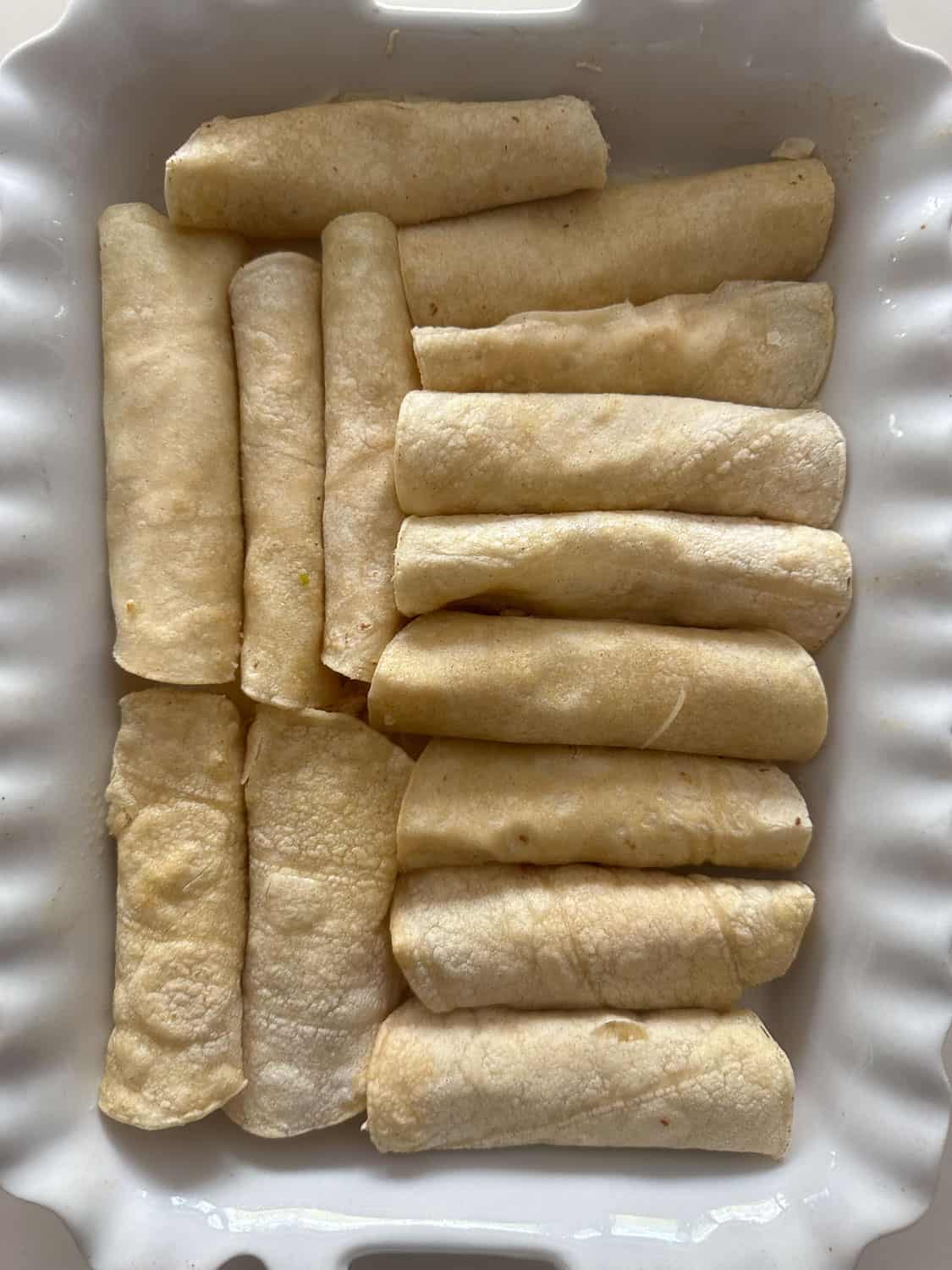 tortillas rolled and placed in white baking pan 