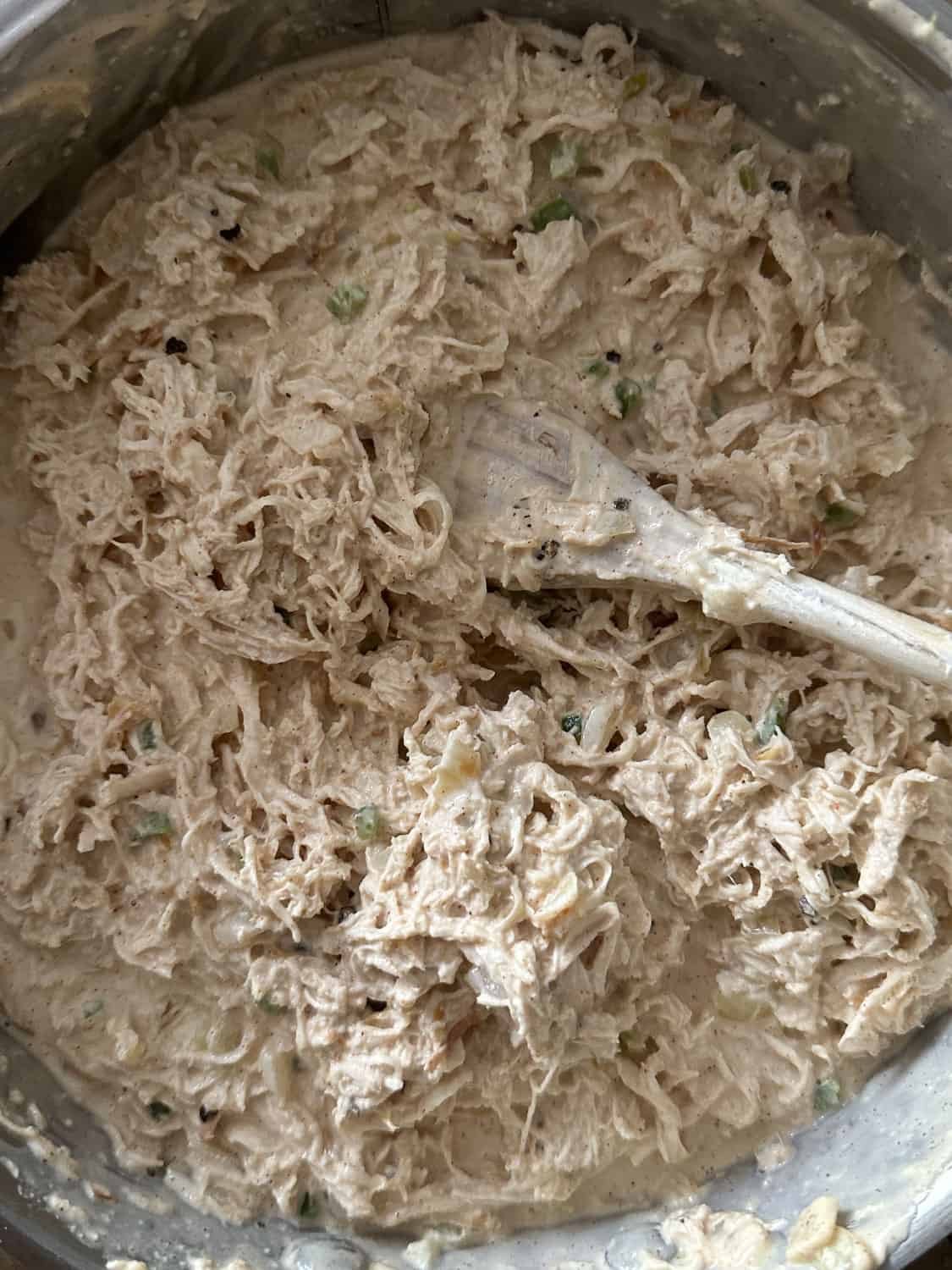 shredded chicken in pan with sauce and spoon 