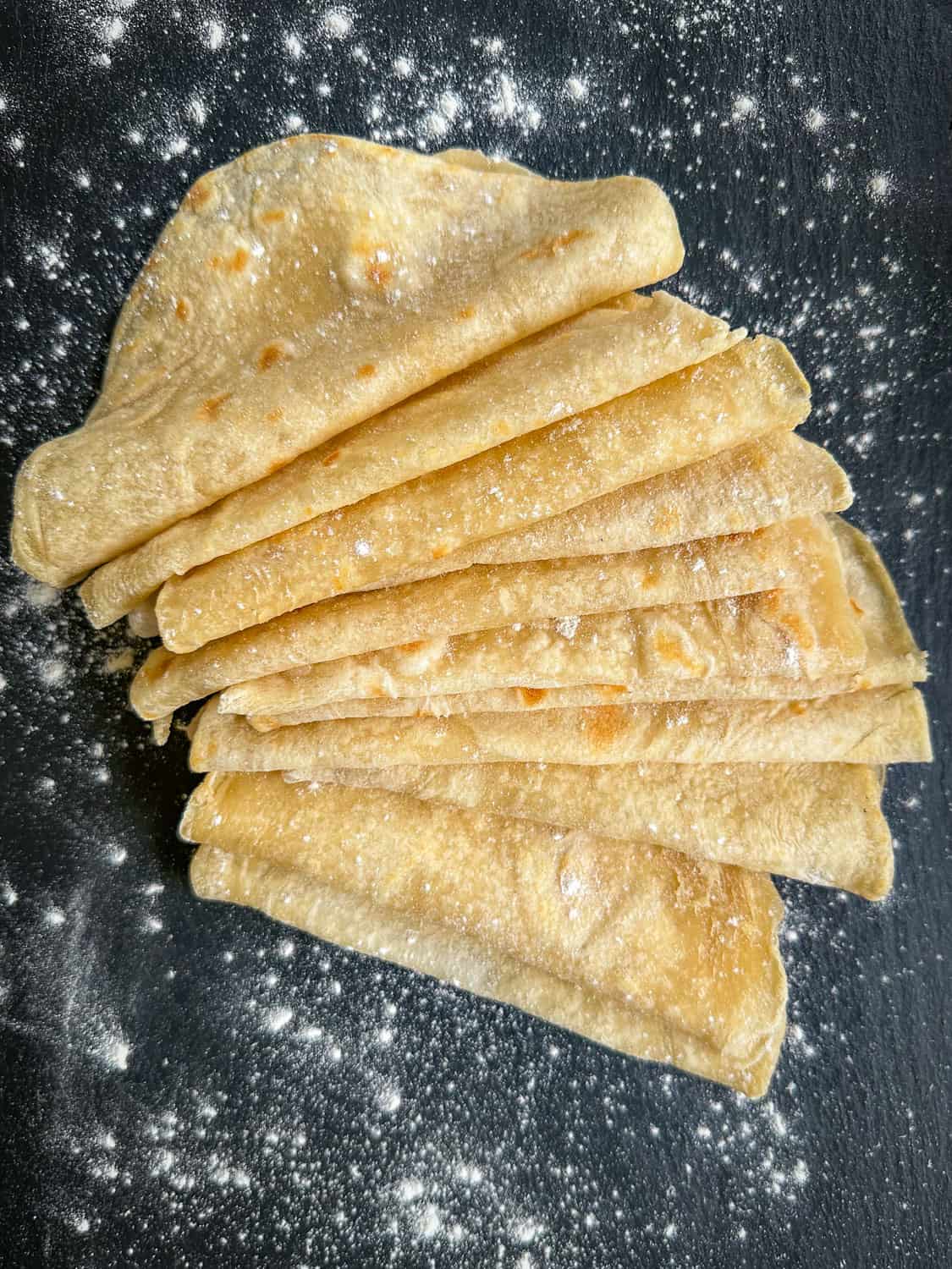 cooked soft flour tortillas on black tray