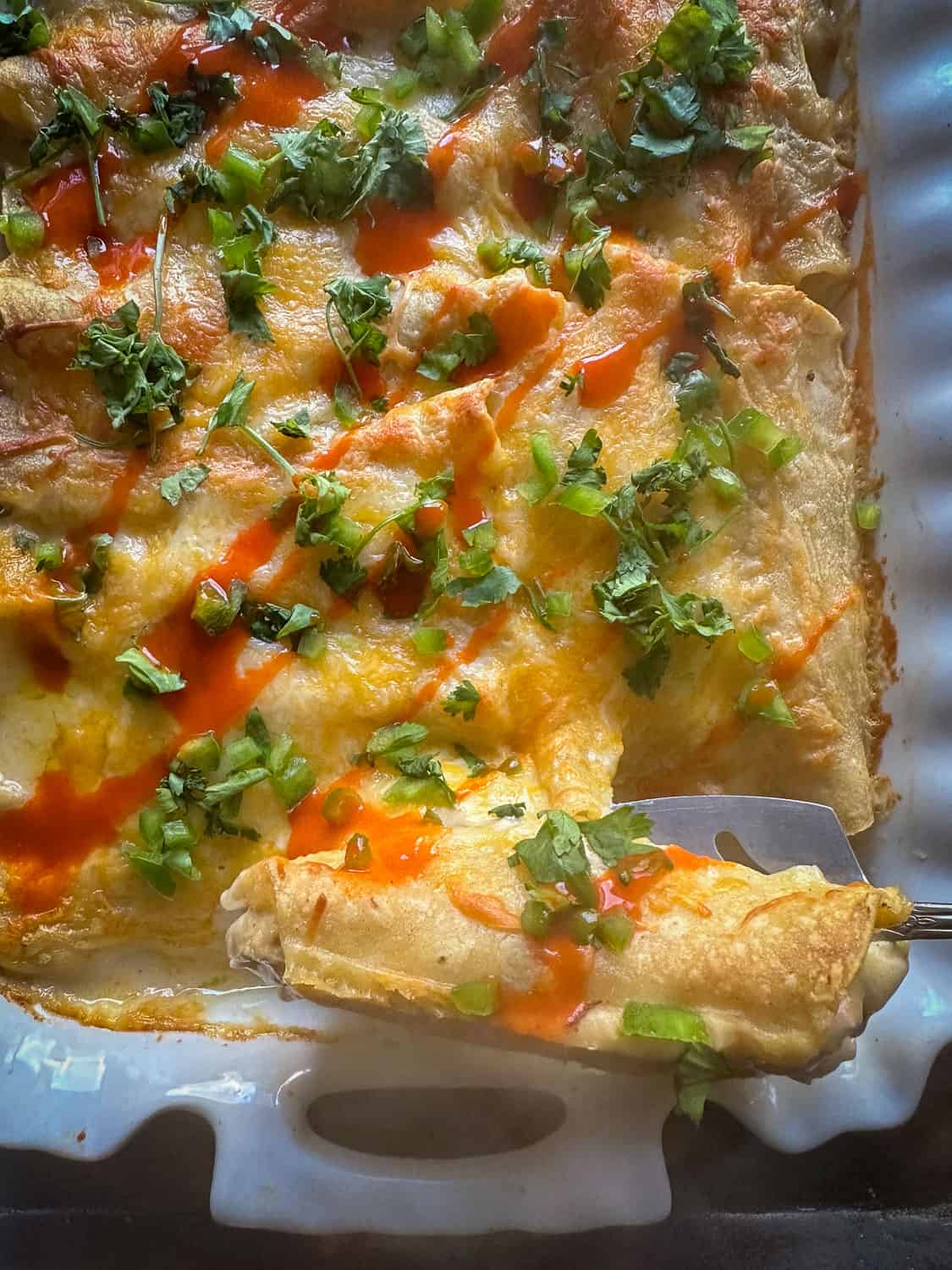 Enchiladas topped with cilantro and hot sauce 