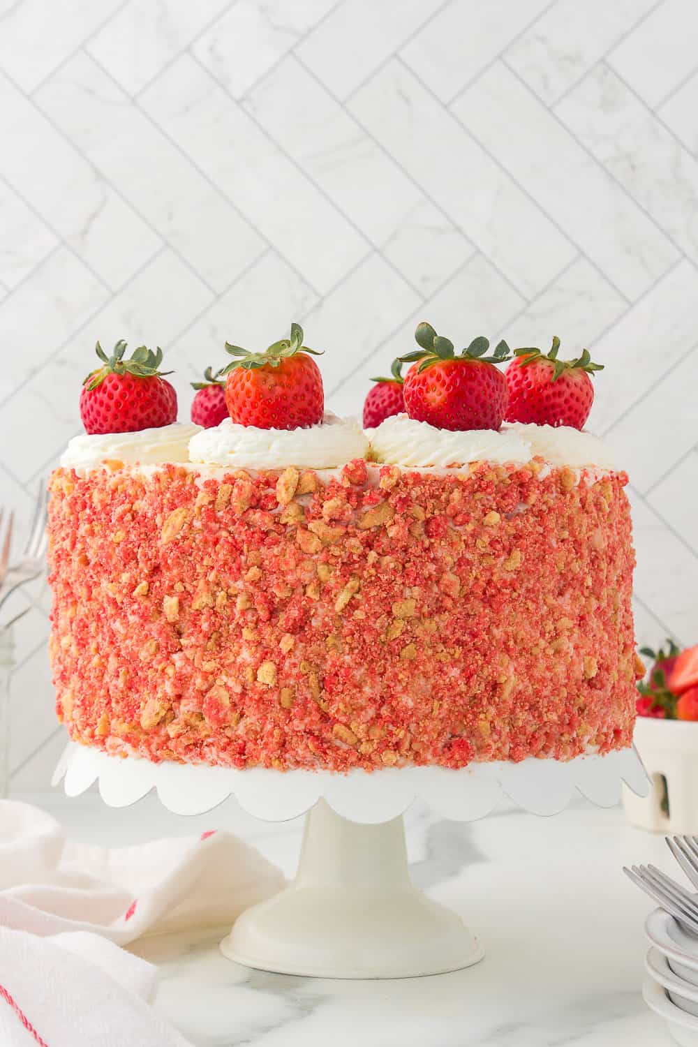 decorated strawberry crunch cake on white cake stand