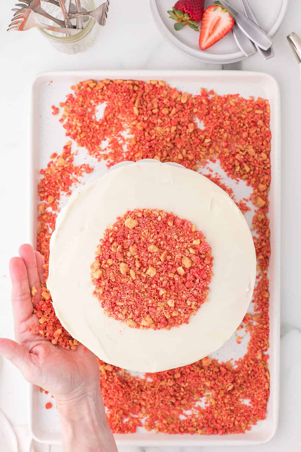 adding strawberry crunch to top of frosted cake