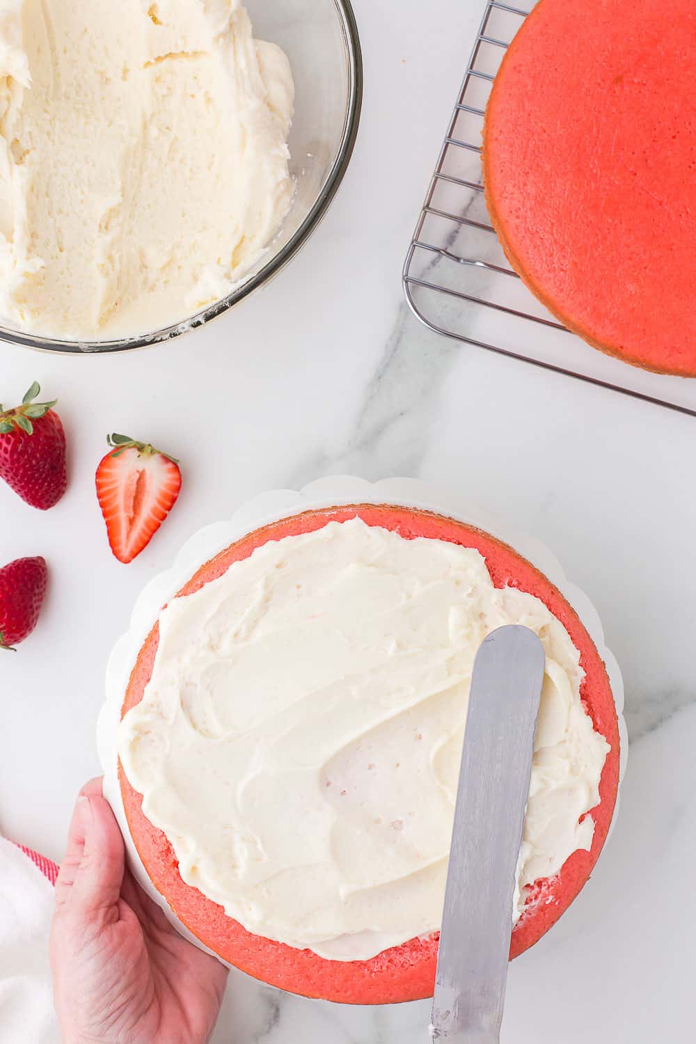 adding buttercream filling to layer of strawberry cake