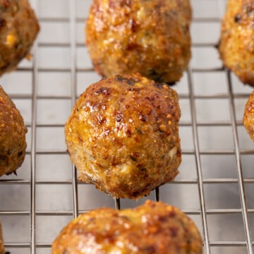 close up side view of baked turkey meatballs on wire rack