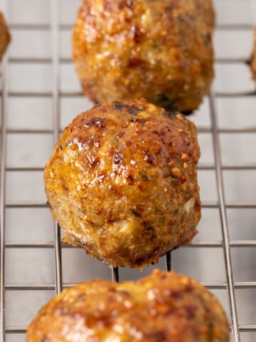 close up side view of baked turkey meatballs on wire rack
