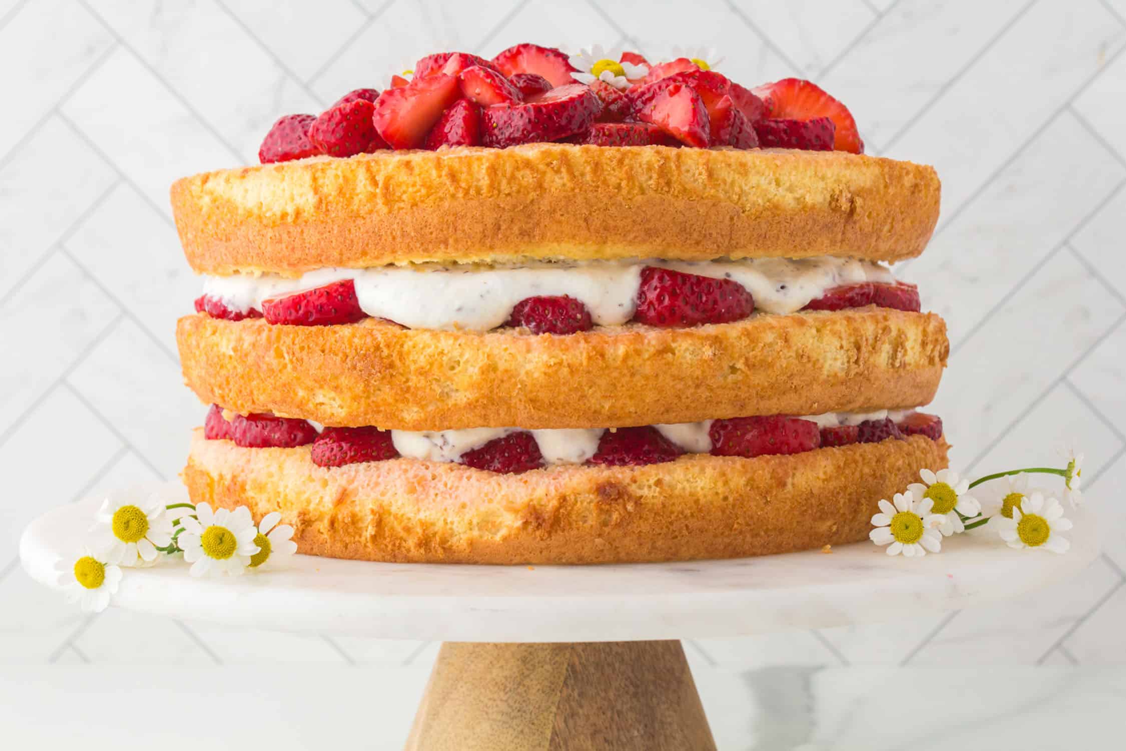side view of italian strawberry cake on white cake stand