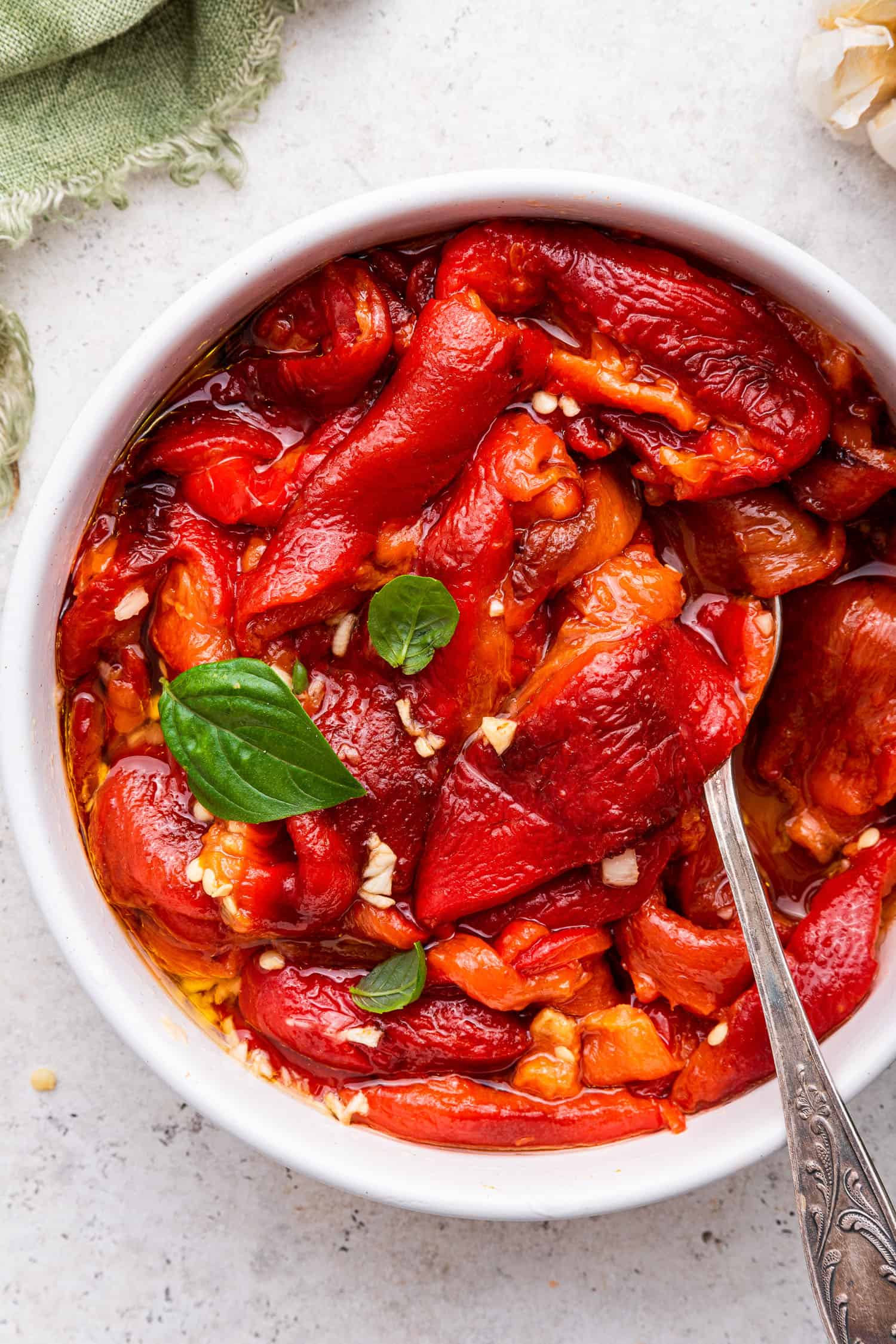 close up top view of roasted red peppers in white bowl with spoons