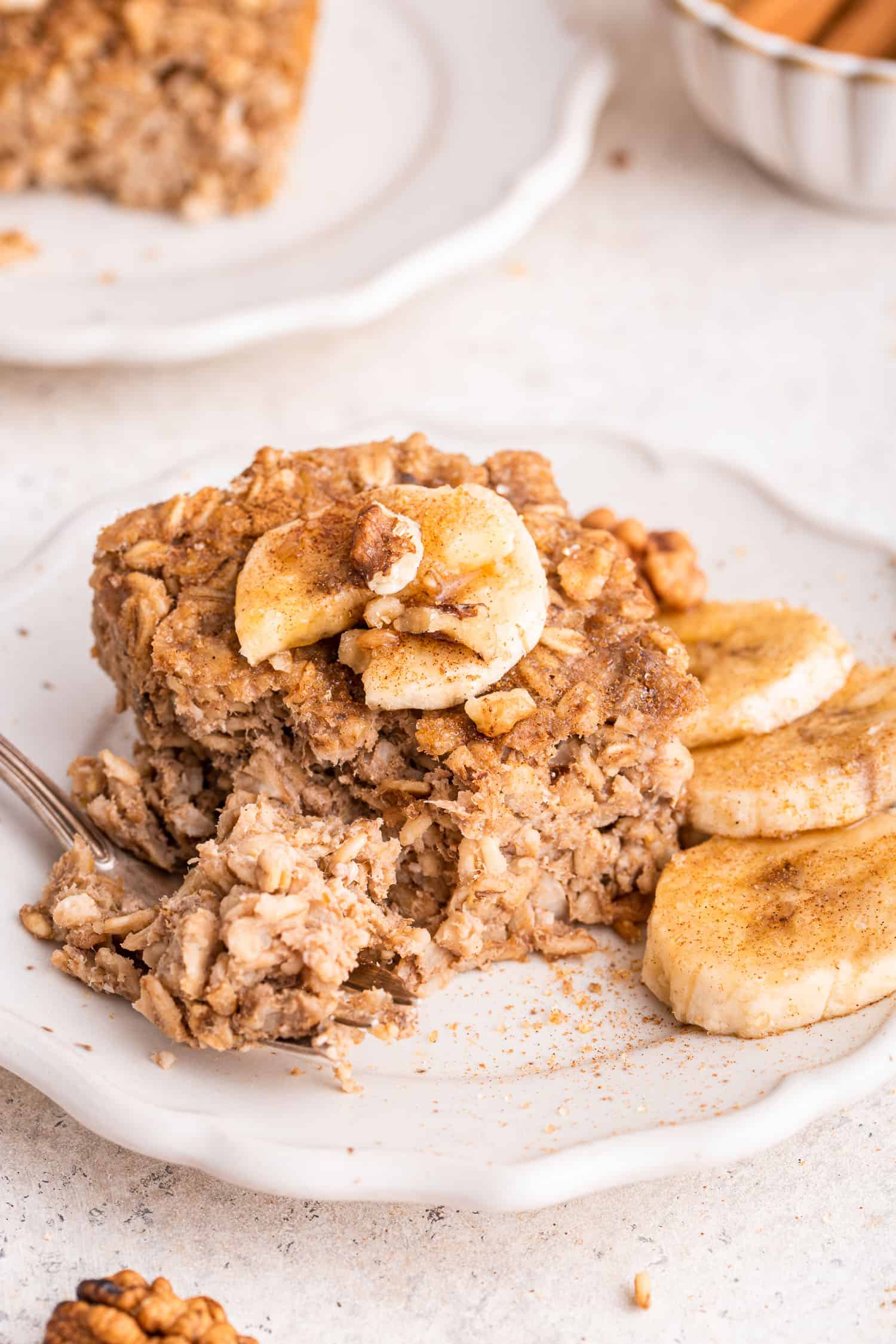 side view of baked oats on white dish with bananas