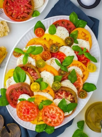 top view of caprese salad on white platter with navy napkin