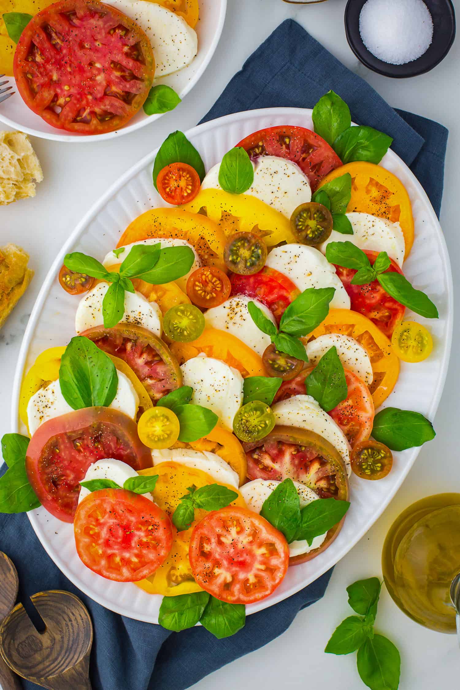 top view of caprese salad on white platter with navy napkin