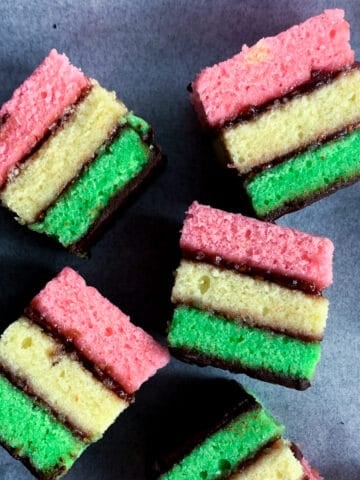 several italian rainbow cookies on black tray
