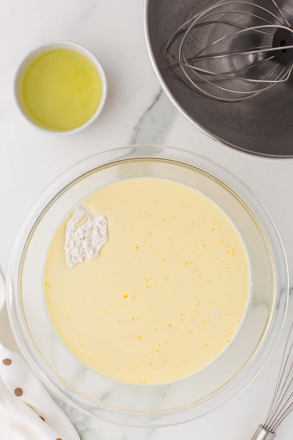 adding flour to wet ingredients in glass bowl