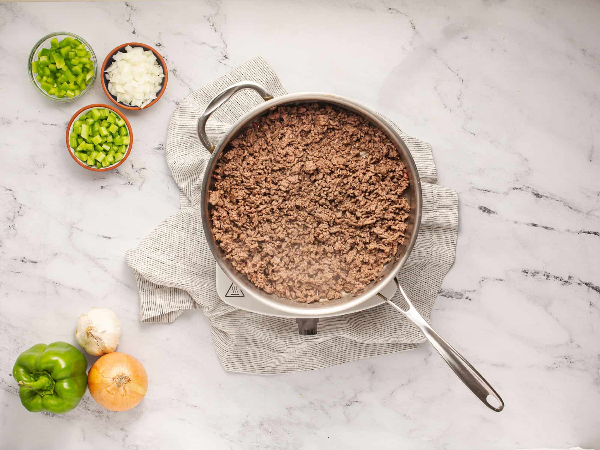 browned meat in pan with vegetables on table