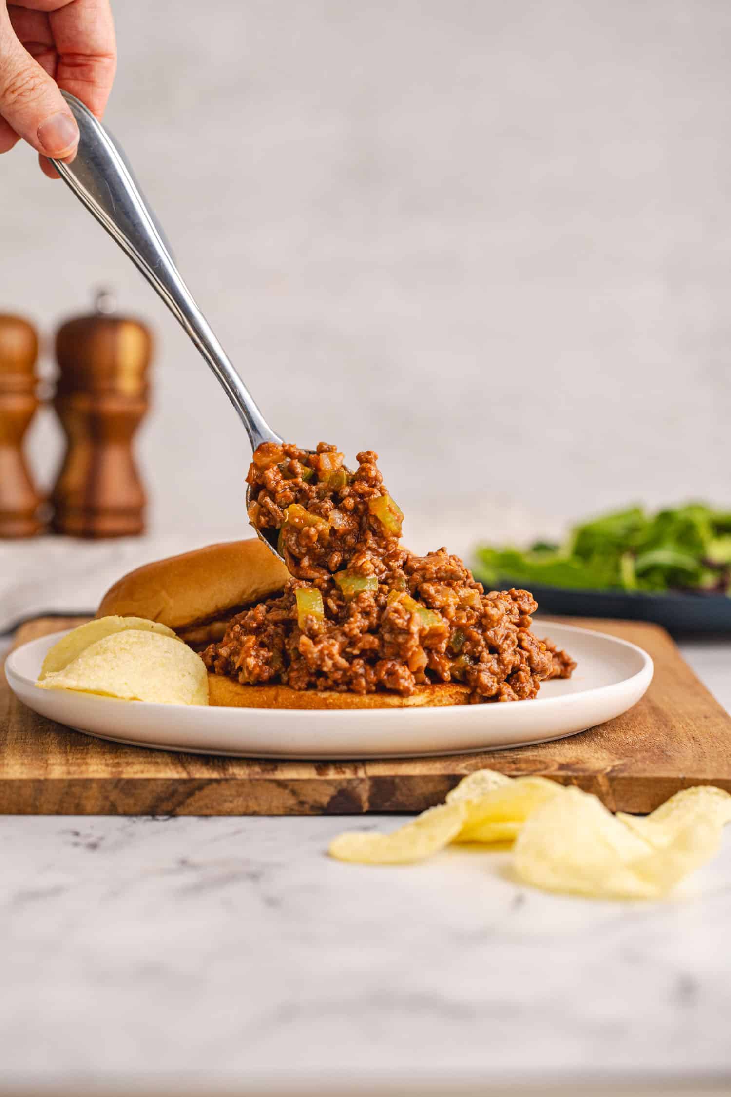 spooning sloppy joe meat onto bun