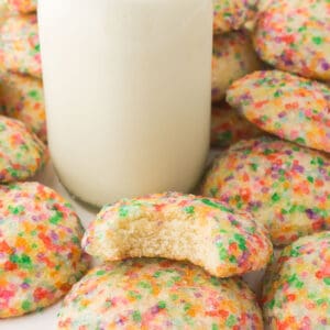 cookies surrounding a tall carafe of milk
