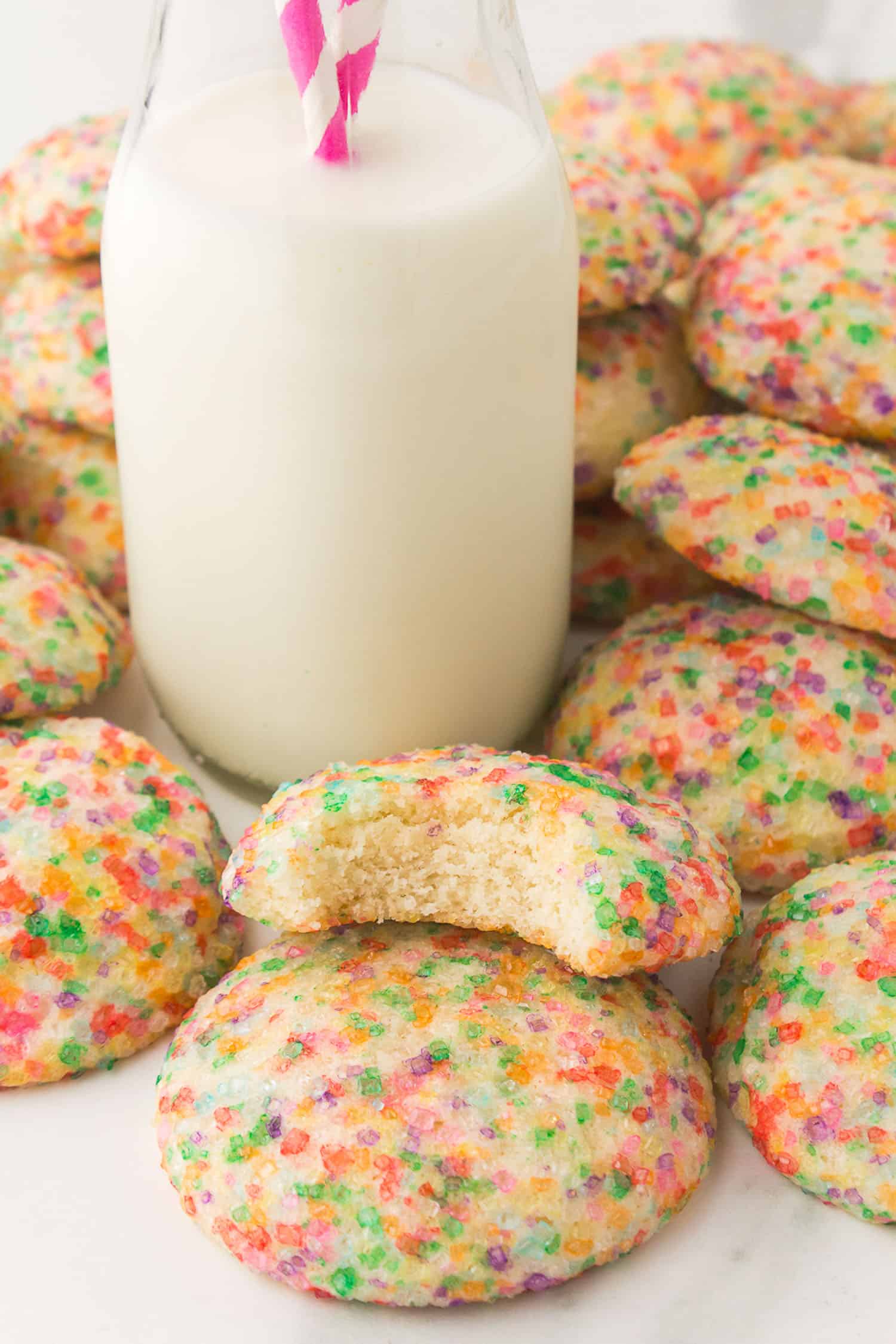 cookies surrounding a tall carafe of milk