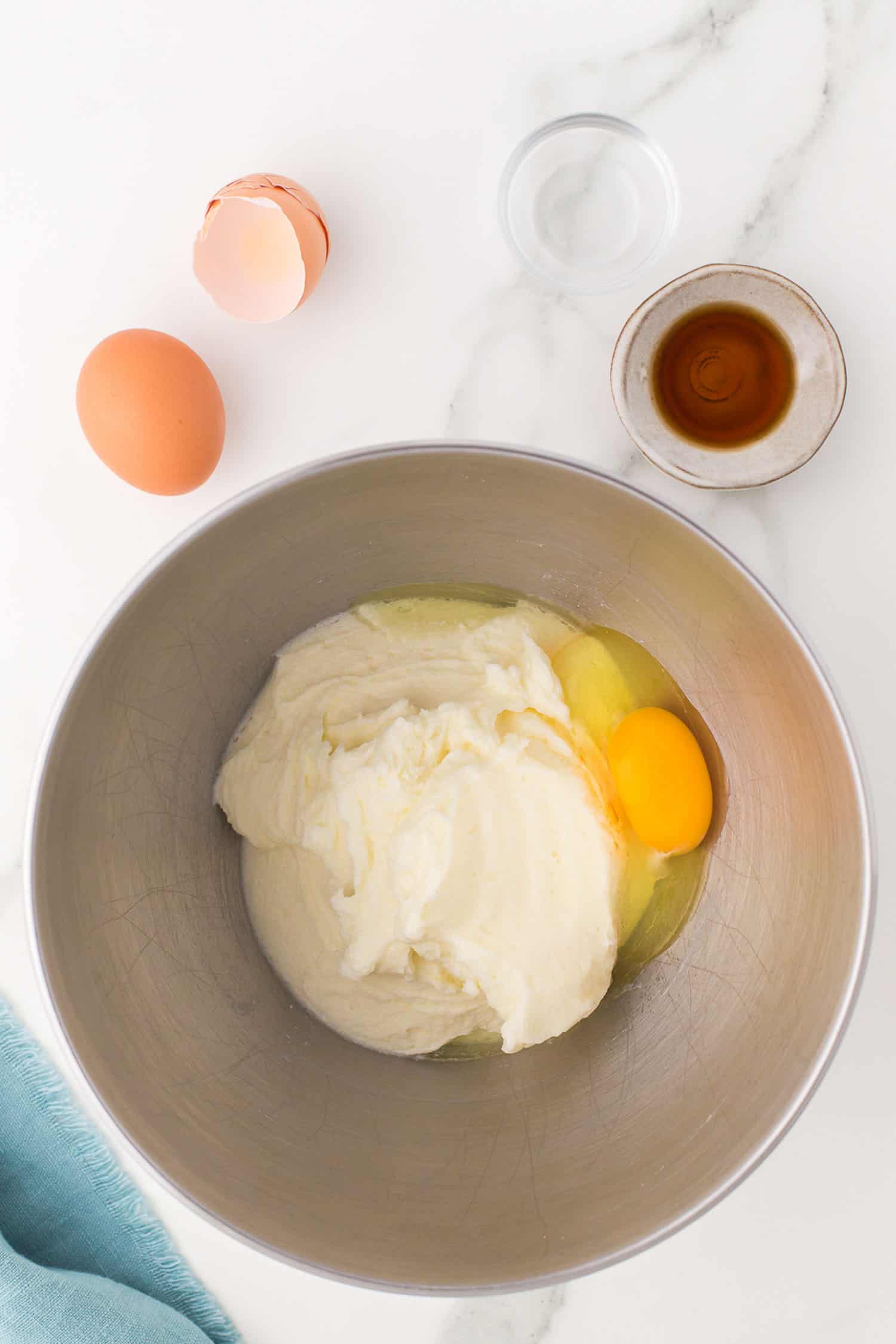 adding eggs, to butter/sugar/sour cream mixture in bowl