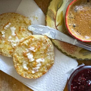 freshly toasted and buttered English muffin on paper napkin with knife