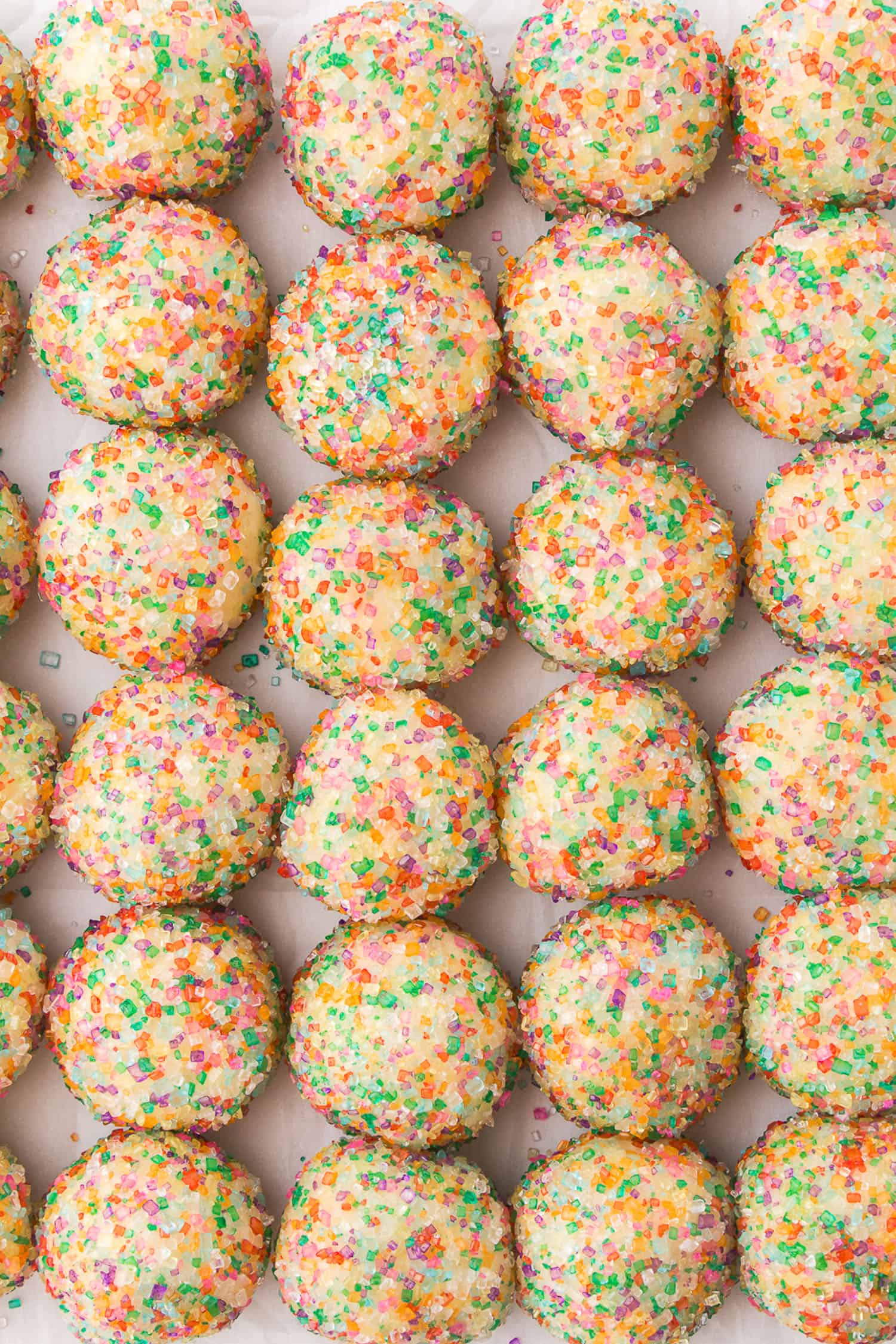 balls of cookies dough with rainbow sugar ready to be baked