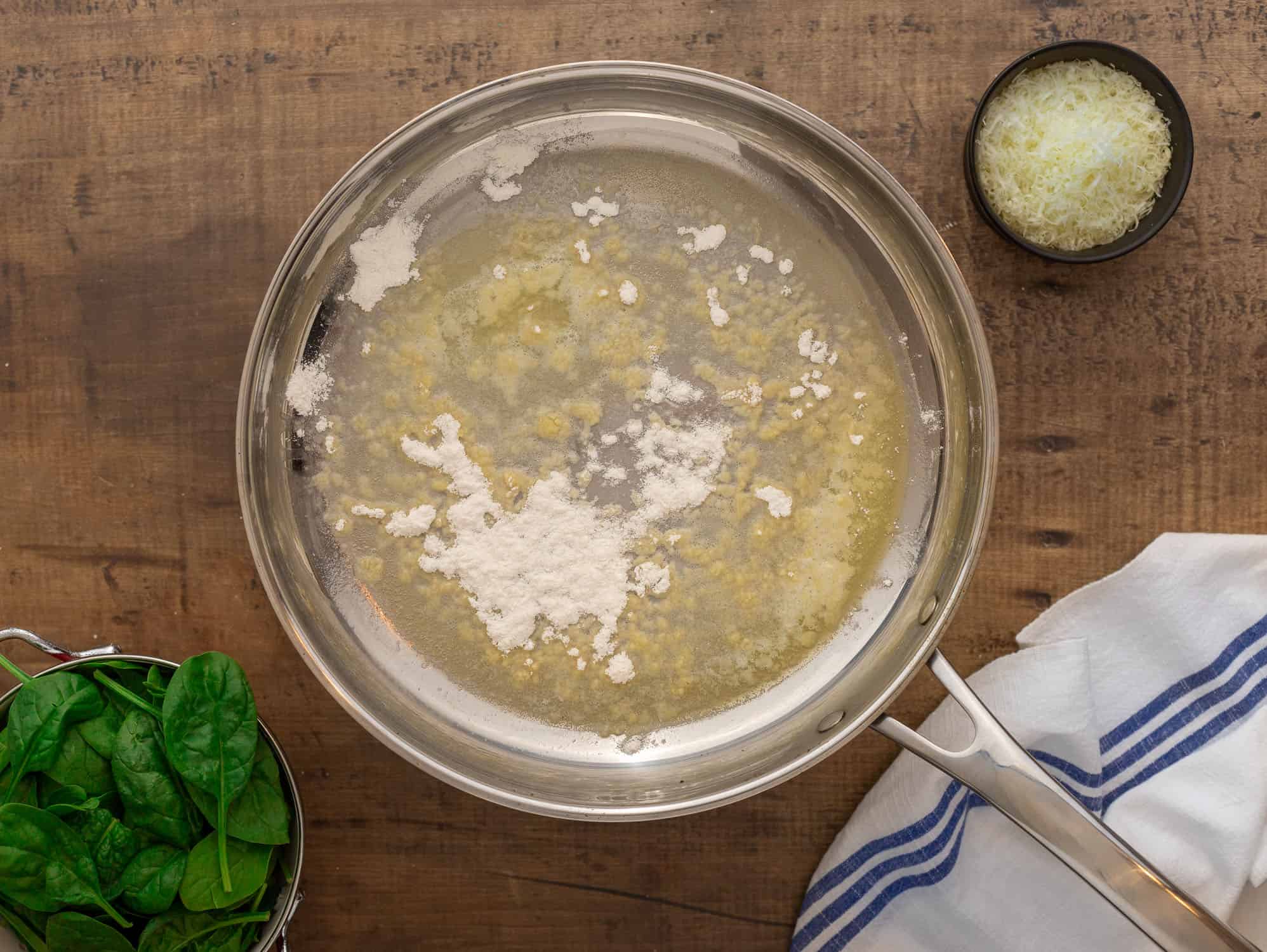 Adding flour to butter in silver pan. 