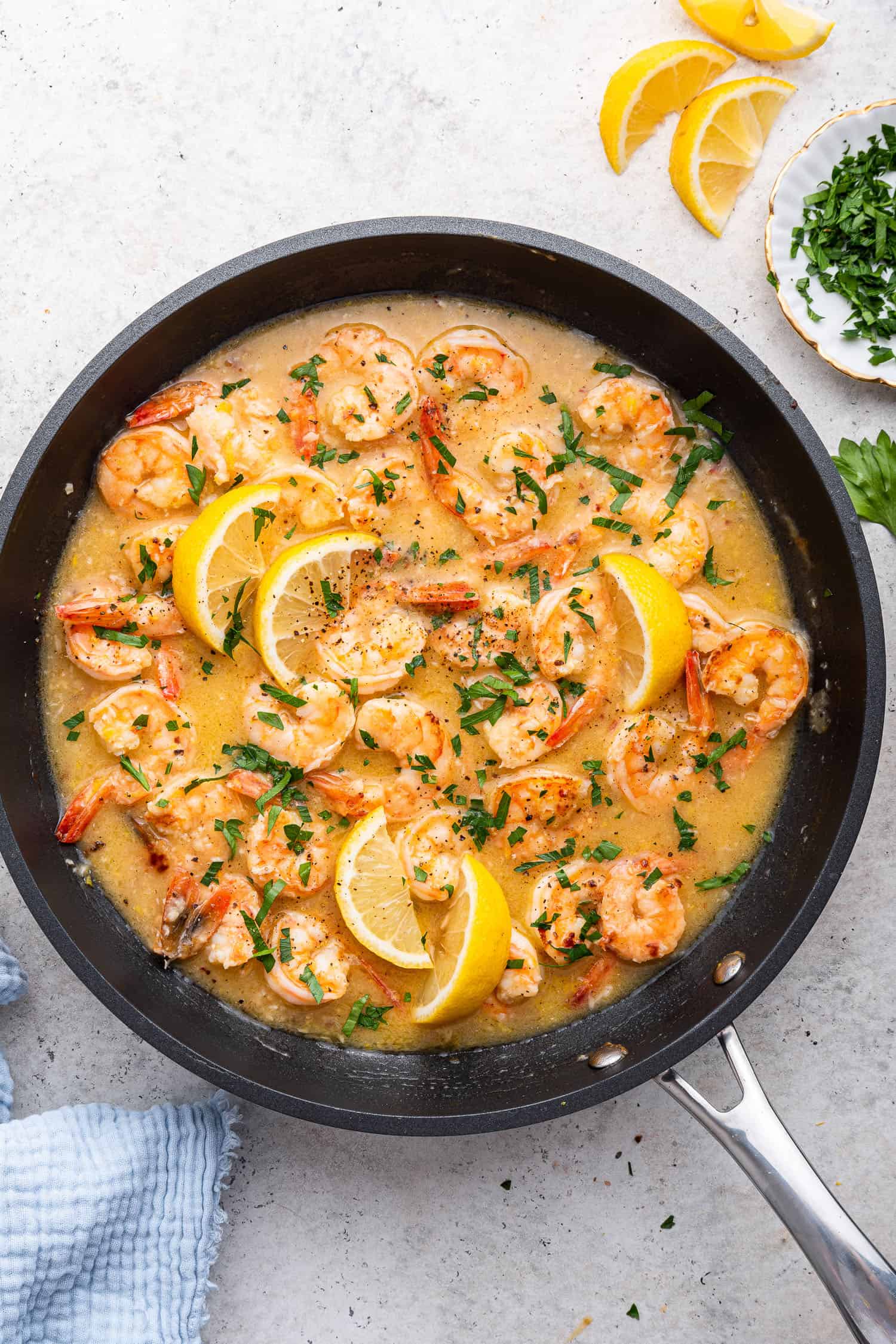 shrimp lemon sauce in black pan with lemon wedges and parsley