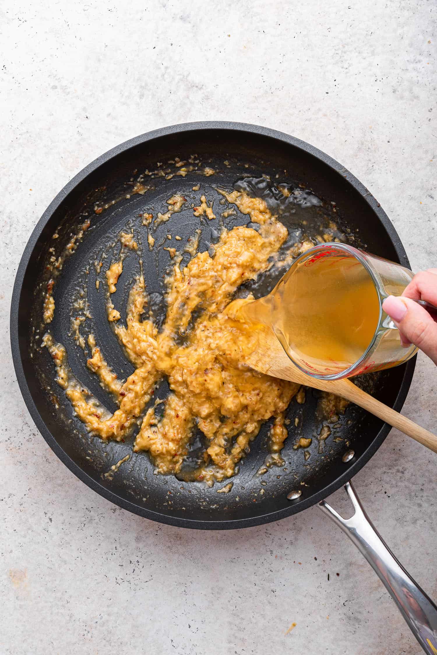 pouring stock in pan to make roux