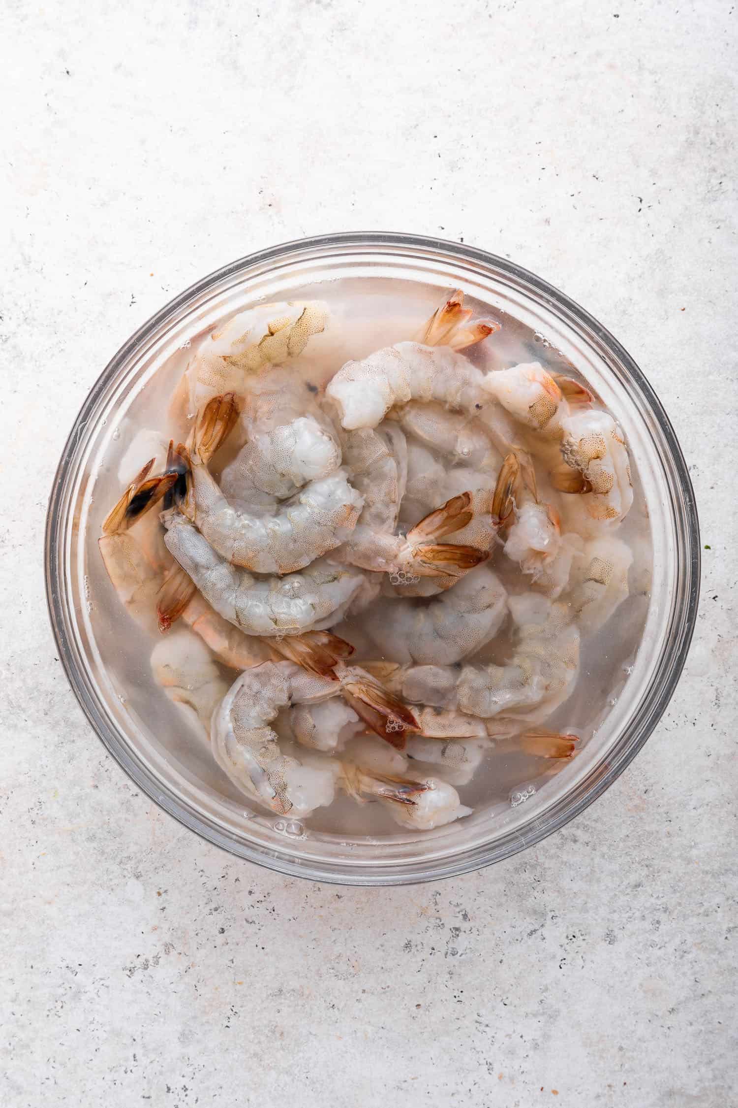 raw shrimp marinating in glass bowl
