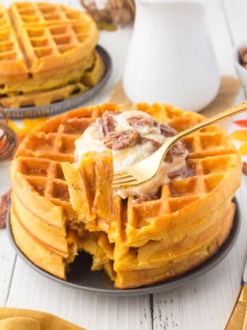 gold forkful of pumpkin waffles from nearby plate of waffles